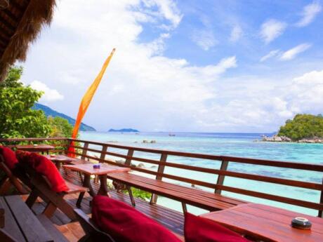 A deck with tables directly next to the water on a sunny day.