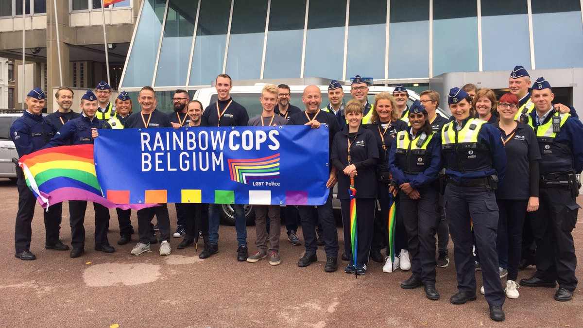 The rainbow cops team of Belgium posing with the rainbow flag