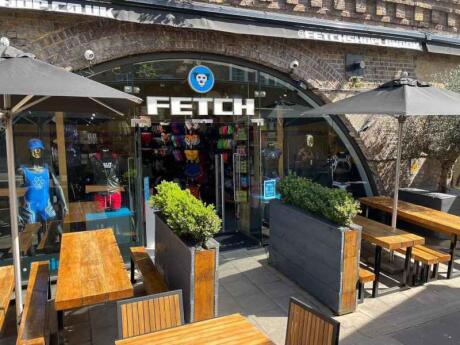 Sitting area of Fetch, with the entrance and wooden tables, a cool gay shop in London.