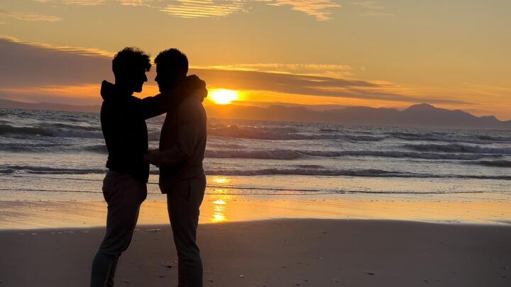 Gay couple on beach at sunset