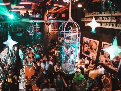 A packed dance floor with a giant birdcage with people dancing in it at S-Cape gay club in Athens.