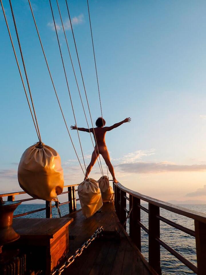 Man experiencing freedom at the tip of a wooden boat.