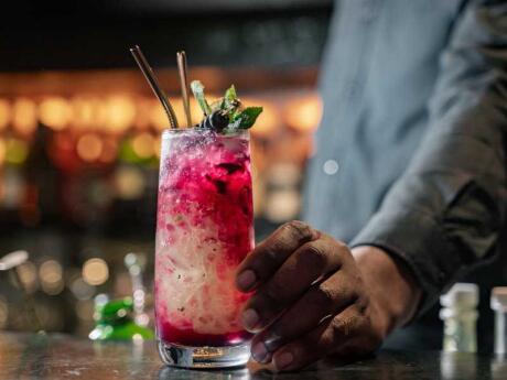 A close up of a waiter's hand delivering a fancy pink cocktail at the Liquid Blue gay bar in Johannesburg.