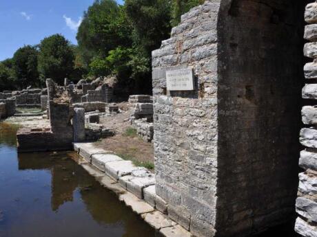 Stone ruins next to water on a sunny day.