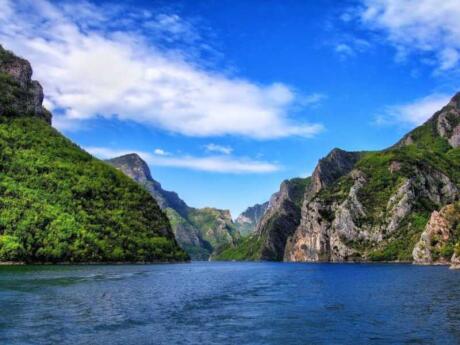 A rocky mountainous landscape as seen from the water on a beautiful sunny day with blue skies.